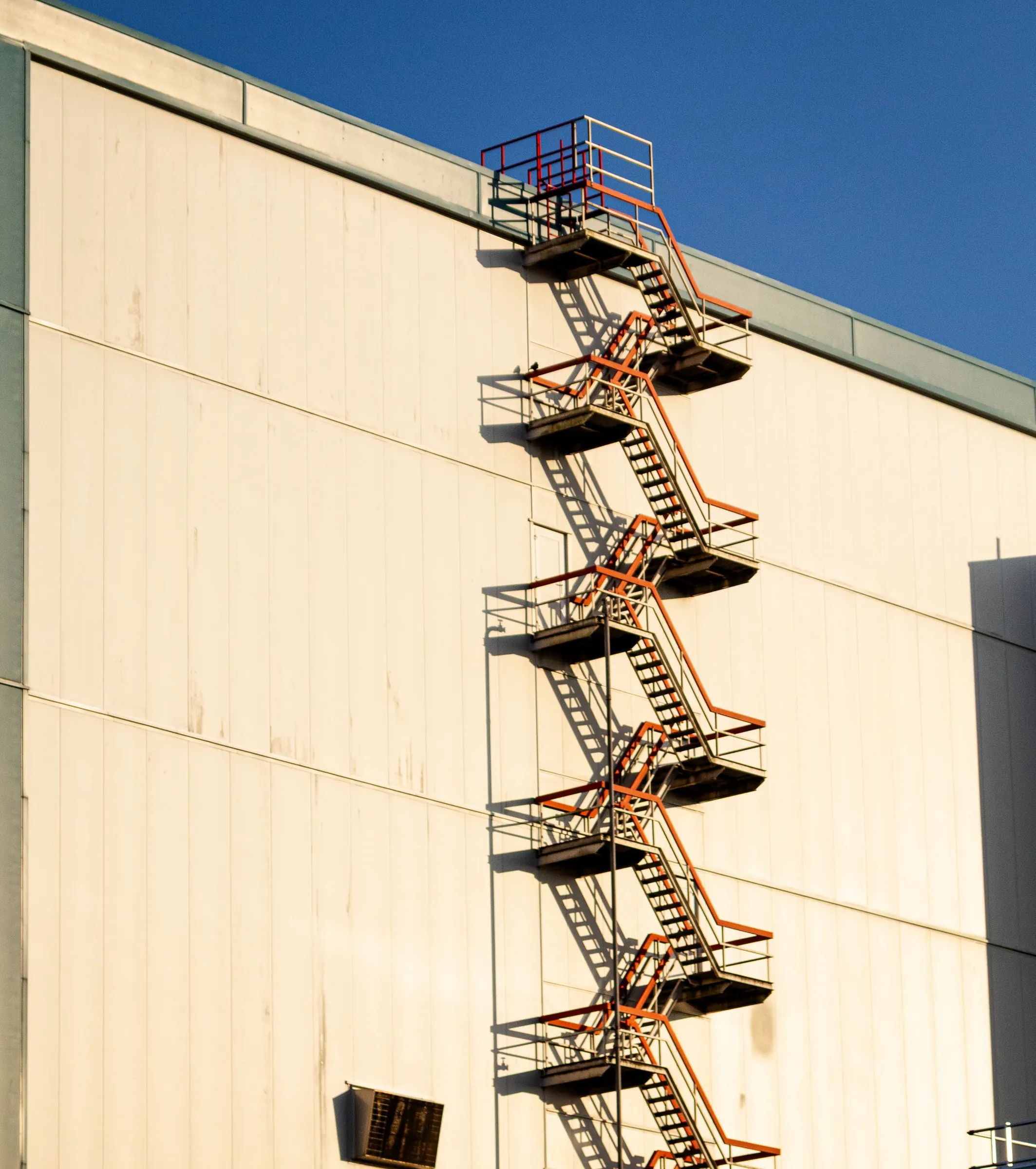 Außenliegende Fluchttreppe an der hellen Fassade eines Gewerbebaus