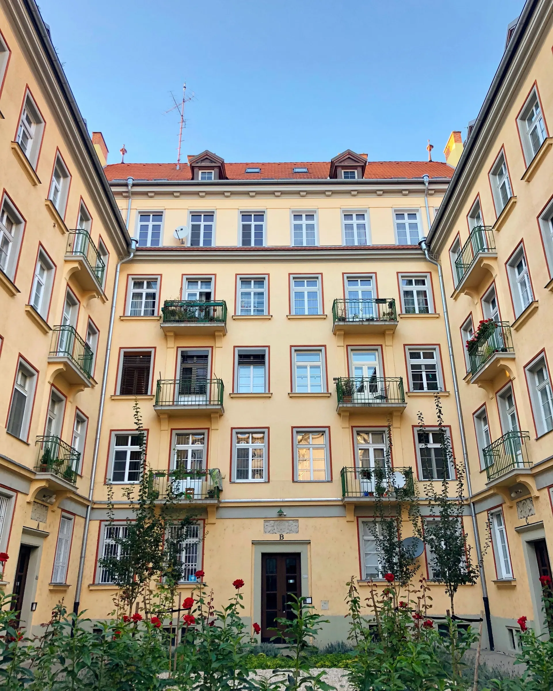 Mehrgeschossiges Wohnhaus mit Balkonen um einen begrünten Innenhof