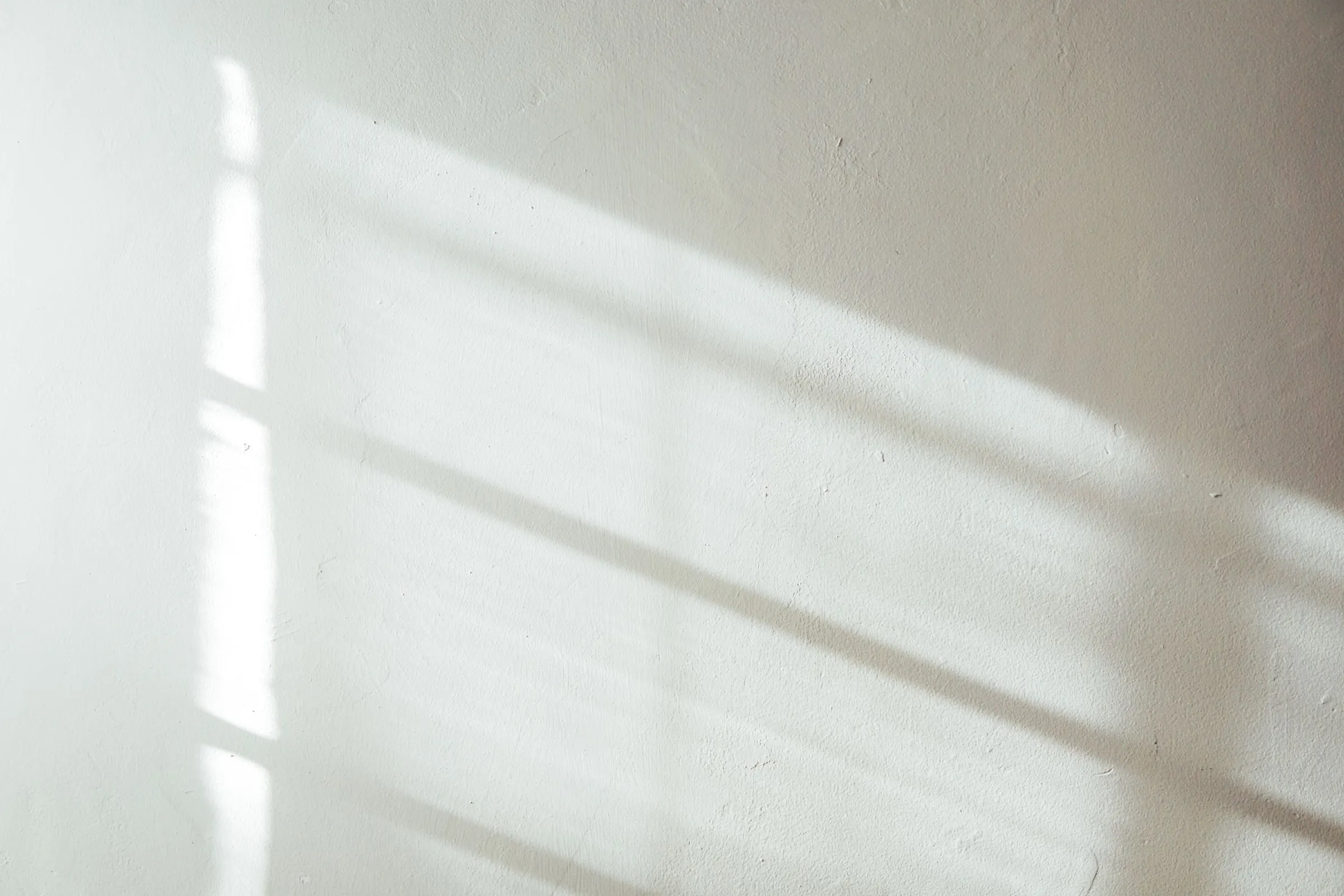 Weiße Wand mit Lichtbahnen und weichen Schatten