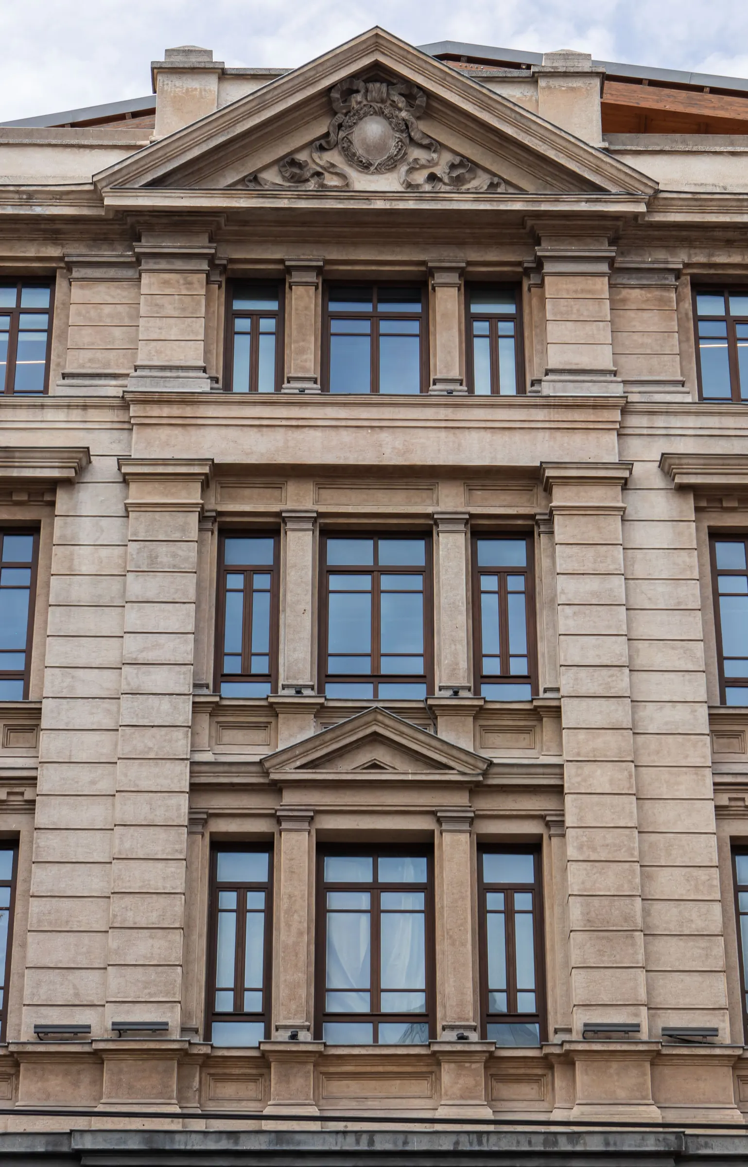 Symmetrische Steinfassade eines historischen Gebäudes mit gleichmäßigen Fensterachsen