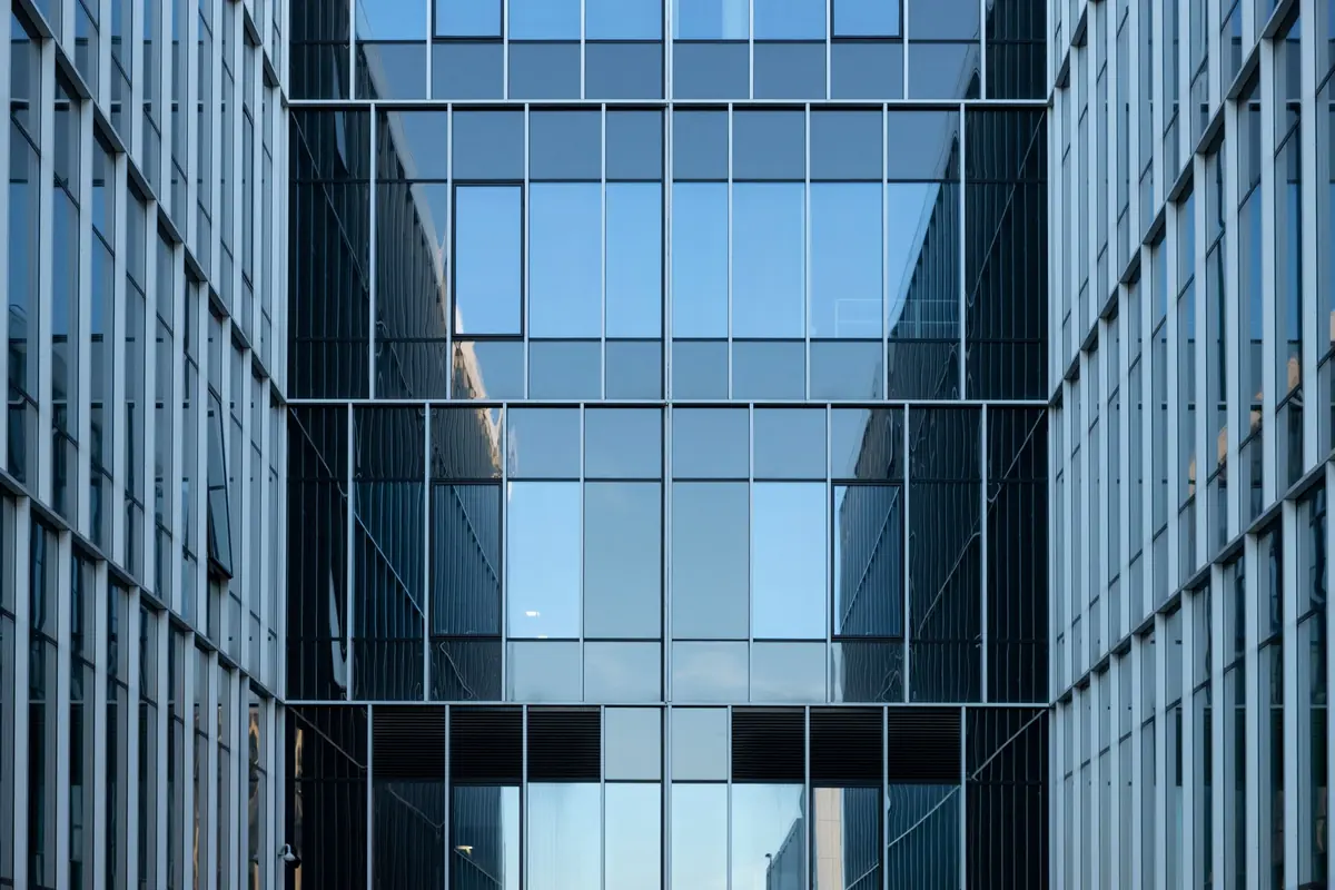 Moderne Glasfassade mit Spiegelungen zwischen zwei Bürogebäuden